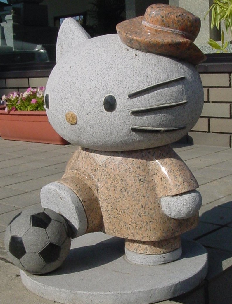 Granite stone statue of Hello Dead Kitty playing soccer. 06jan1.