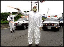 Local Tokiamura police direct traffic while in full silver radiation suits.