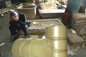 An Iraqi
mourns the destruction of priceless cultural artifacts
behind untouched oil barrels.